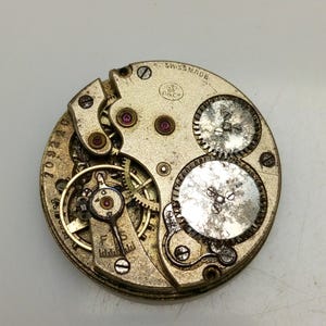 Pode incluir: Close-up de um movimento de rel&oacute;gio dourado com engrenagens intrincadas e o texto "Swiss Made" e "F.P.Co."