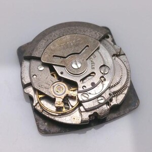 Puede incluir: Primer plano de un movimiento de reloj vintage, mostrando engranajes, resortes y la marca "SEIKO". Los componentes met&aacute;licos son plateados y dorados, revelando los detalles internos del reloj.