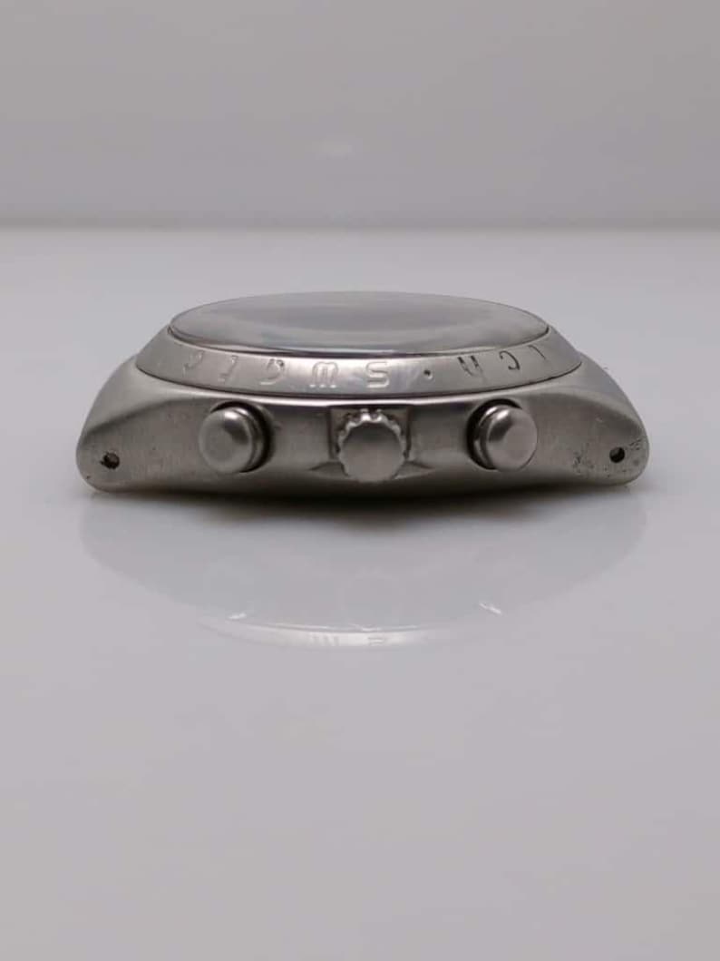 May include: A silver-toned wristwatch with a round face and three buttons on the side. The watch has a dark face and a metallic band. The watch is a classic design, suitable for everyday wear.