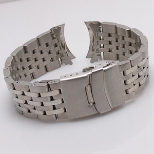 Könnte beinhalten: Ein silbernes Metall-Armband mit einer Schließe. Das Armband besteht aus einer Reihe kleiner, ineinandergreifender Glieder.