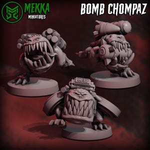 Op de afbeelding: Drie grijze miniatuurfiguren van Bomb Chompaz, elk met een dreigende grijns en scherpe tanden. De figuren zijn gemonteerd op ronde bases en hebben verschillende wapenopzetstukken, waaronder raketten en cilindrische apparaten. De tekst "MEKKA MINIATURES" en "BOMB CHOMPAZ" zijn zichtbaar.