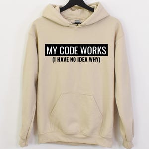 May include: A beige hoodie with a black box that says "MY CODE WORKS (I HAVE NO IDEA WHY)"