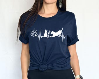 May include: A navy blue t-shirt with a white graphic of a cat and dog with a heart between them, a paw print, and a heartbeat line.