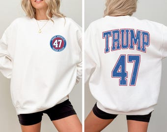 Puede incluir: Sudadera blanca con un círculo azul y rojo en la parte delantera que dice "Make America Trump Again 47". La parte posterior de la sudadera tiene el texto "Trump 47" en azul y rojo.