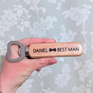 May include: Wooden bottle opener with a metal cap opener. The handle is engraved with "DANIEL BEST MAN" and a bowtie.