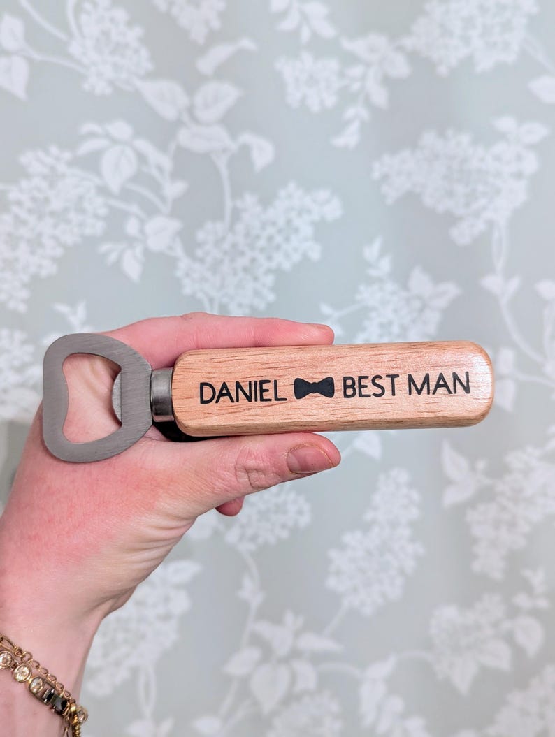 May include: Wooden bottle opener with a metal cap opener. The handle is engraved with "DANIEL BEST MAN" and a bowtie.