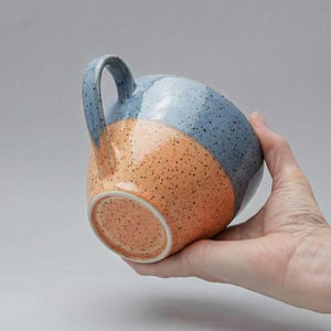 Può includere: Una tazza di ceramica bianca con un manico nero e la scritta "But First, Coffee" in stile scritto a mano. La tazza è su una superficie bianca. La tazza è alta circa 10 cm.