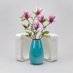 May include: A white ceramic mug with a black handle and the text "But First, Coffee" in a bold, black font. The mug is set against a blurred background, suggesting a cosy setting.