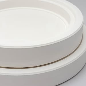 May include: A stack of two circular white ceramic plates with smooth, matte surfaces. Each plate features a wide, flat rim and a recessed centre section, creating a clean, uniform appearance with no additional patterns or decorative elements.