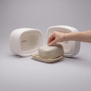 Peut inclure: Une boîte à pain en céramique blanc mat avec une ouverture rectangulaire et un beurrier beige moucheté séparé avec son couvercle assorti. Le beurrier présente une surface texturée avec des taches brun foncé et un petit bouton sur le couvercle.