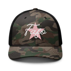 May include: Camouflage trucker hat with a black mesh back and a curved brim. The front features a pink star with the word "Fafo" in white script. The hat is designed for casual wear.