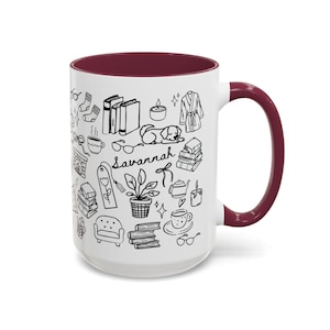 May include: White ceramic mug with a claret interior and handle. The mug features black line art of books, a dog, a fireplace, and the word "Savannah".