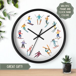May include: A circular wall clock with a black frame and a white face. The clock face displays illustrations of skiers in colourful outfits. The clock hands are black. The text "GREAT GIFT!" is at the bottom.