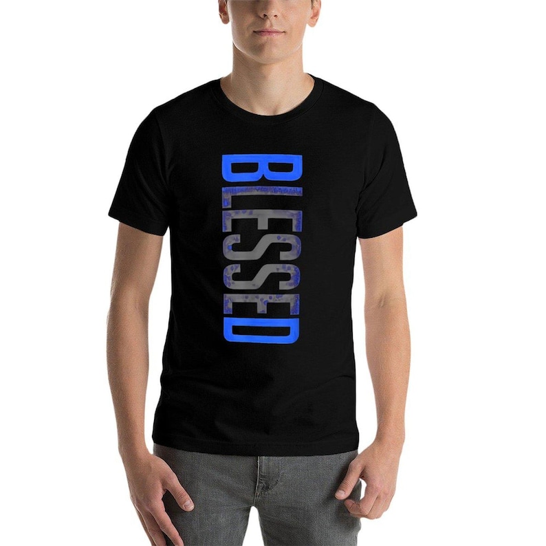 May include: Black t-shirt with the word "BLESSED" printed vertically in blue. The text has a textured, watercolor-like appearance. The shirt is short-sleeved and appears to be made of a soft material.