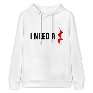 May include: White hooded sweatshirt with the text "I NEED A" in black, and a red musical note symbol. The sweatshirt has a front pocket and a drawstring hood. A casual, comfortable garment for everyday wear.