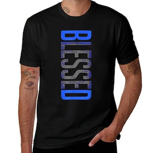 May include: Black t-shirt with the word "BLESSED" printed vertically in a blue and gray color scheme. The text is centered on the front of the shirt. The shirt has short sleeves and a crew neck.