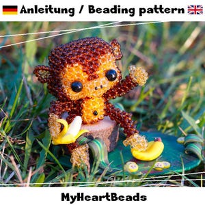 May include: A beaded monkey figurine with a yellow banana. The monkey is brown and orange, with black eyes. The figurine is sitting on a small wooden slice and a green base. The text "Anleitung / Beading pattern" is at the top.
