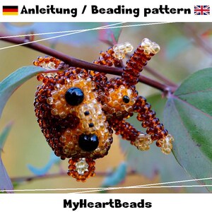 May include: A beaded monkey figure crafted from small brown and translucent amber beads with black bead eyes and nose. The text "Anleitung / Beading pattern" and "MyHeartBeads" is visible on the image along with German and British flags.