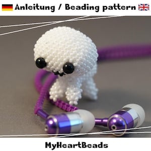 May include: A small white beaded creature figure with two large black eyes, positioned next to purple wired earbuds with silver accents. The text "Anleitung / Beading pattern" and "MyHeartBeads" is visible in the image.