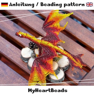 May include: A beaded dragon figurine crafted with small yellow, orange, and red beads, featuring outstretched wings and a long tail. The text "Anleitung / Beading pattern" and "MyHeartBeads" is visible at the top and bottom of the image.