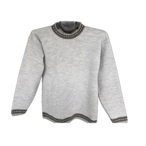 Puede incluir: Un suéter de manga larga de color gris claro con cuello redondo. La prenda está decorada con un borde de patrón geométrico en color marrón oscuro y blanco a lo largo del cuello, los puños de las mangas y el dobladillo inferior.