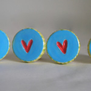 May include: Four blue and green ceramic knobs with red heart designs.