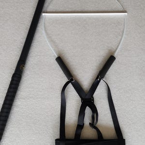 May include: Black freestyle harness with a white bar and a black pole. The harness has adjustable straps and a waist belt with the text "Freestyle Harness" in gold lettering.