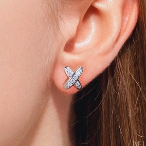 May include: Silver earrings with a small, clear crystal cross design.