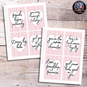 Può includere: Due fogli di carta con sfondi a righe rosa e bianche e disegni a forma di cuore. Ogni cuore contiene una frase in corsivo nero, come "Sogna in grande, tesoro" e "Amore, amicizia e femminismo."