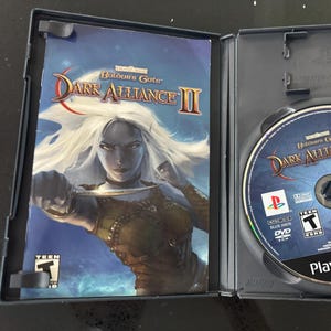 May include: A PlayStation 2 game case for Baldur's Gate: Dark Alliance II. The front cover features a female elf character holding a dagger. The back cover shows the game's logo and a description of the game.