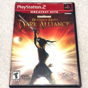 May include: A PlayStation 2 game case for "Baldur's Gate: Dark Alliance" from the "Greatest Hits" series. The cover shows a female warrior with a sword against a fiery backdrop. The game is rated "Teen" by the ESRB.