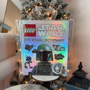 Puede incluir: Un libro LEGO Star Wars: The Visual Dictionary, actualizado y ampliado, está encerrado en plástico transparente. La portada presenta el logotipo de LEGO, el título de Star Wars e imágenes de personajes y vehículos LEGO Star Wars. Se incluye una minifigura exclusiva de Luke Skywalker.