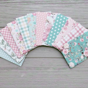 May include: A collection of rectangular paper envelopes arranged in a fan shape. The envelopes feature various patterns including light blue polka dots, pink gingham, floral prints with roses, teal plaid, and white polka dots on a teal background.