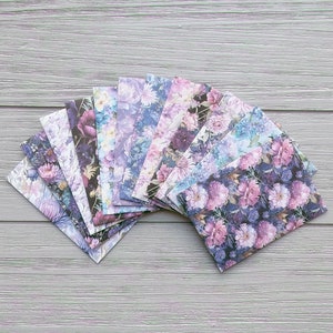 May include: A collection of rectangular envelopes arranged in a fan shape, each featuring a distinct floral pattern in shades of purple, blue, pink, and black. The envelopes display various botanical prints including roses and other garden flowers.