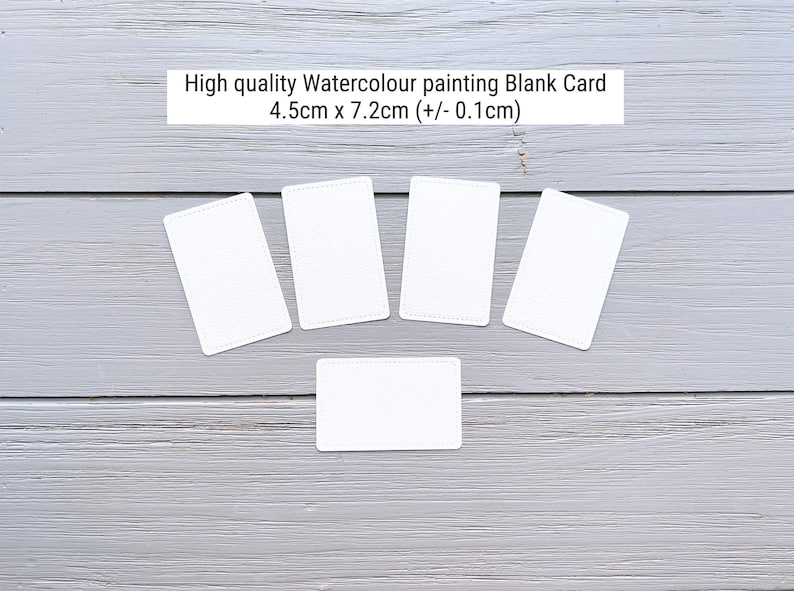 May include: Five white rectangular blank cards for watercolor painting, each measuring 4.5cm x 7.2cm (+/- 0.1cm). The cards feature rounded corners and a smooth surface, arranged in a fan-like pattern with one card positioned horizontally below.