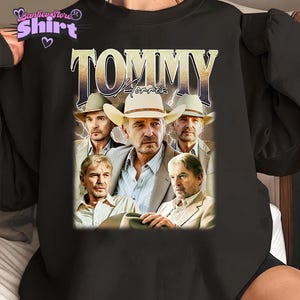 Puede incluir: Sudadera negra de cuello redondo con un gráfico de un hombre con sombrero de vaquero y el texto "TOMMY Morris" en un estilo vintage. El diseño incluye múltiples imágenes del mismo hombre con sombrero de vaquero y traje.