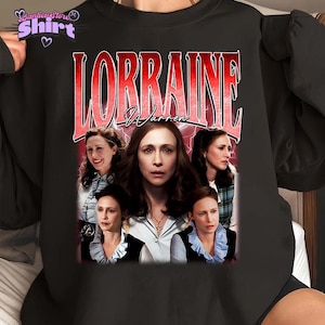 以下が含まれることがあります： 黒いクルーネックのトレーナー。赤色の「LORRAINE WARREN」という名前のグラフィックと、ヴィンテージスタイルのデザインが特徴です。グラフィックには女性の複数の画像が含まれています。トレーナーは濃い色です。