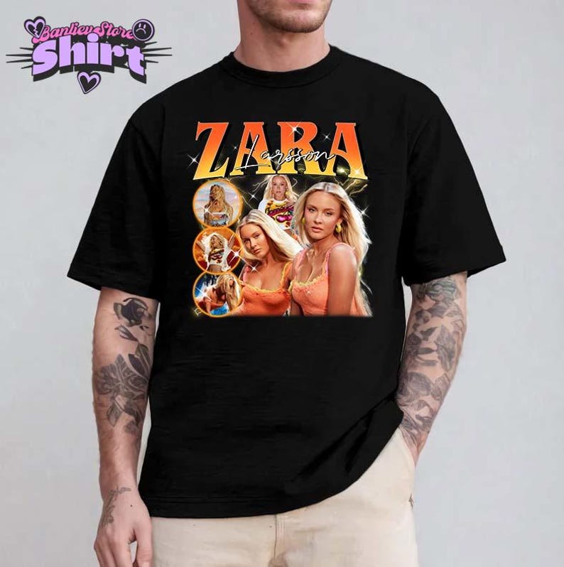 May include: Black t-shirt featuring a graphic of Zara Larsson with the name "ZARA" in orange and yellow lettering. The design includes multiple images of the singer. The shirt is a classic crew neck style.