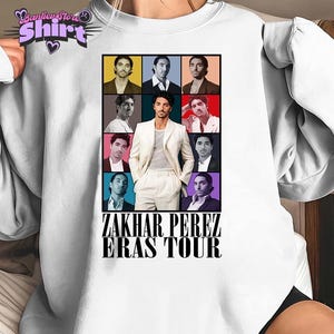 May include: White crew neck t-shirt featuring a collage of images of Zakhar Perez. The design includes a central image of Perez in a white suit, surrounded by smaller images. The text "ZAKHAR PEREZ ERAS TOUR" is printed below the images.