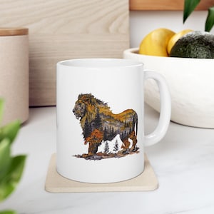 Puede incluir: Taza de cerámica blanca con un diseño de león. La silueta del león está rellena con una escena de bosque en tonos marrones, naranjas y verdes. La taza tiene un asa curva y es adecuada para bebidas calientes.