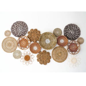 Könnte beinhalten: Eine Auswahl an gewebten Wanddekorationen in verschiedenen Formen und Größen. Die Kollektion umfasst runde, blumenförmige und kugelförmige Designs in natürlichen Braun-, Beige- und Weißtönen. Einige Stücke weisen komplizierte Muster und Texturen auf.