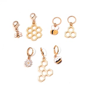 Puede incluir: Un conjunto de siete abalorios dorados con temática de abejas y panales. Los abalorios presentan una abeja, un panal, una flor y un tarro de miel. Los abalorios son perfectos para añadir un toque de fantasía a tus joyas o manualidades.