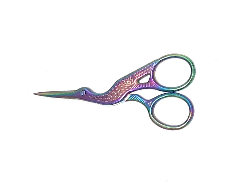 May include: A pair of iridescent rainbow-coloured scissors with a bird design. The scissors have a small hole in the bird's beak.