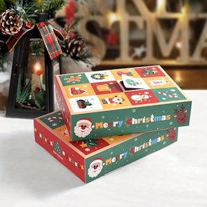 May include: Two stacked Christmas-themed gift boxes. The boxes are red and green with "Merry Christmas" text and Santa Claus illustrations. The top of the boxes feature a grid of festive images, including gingerbread men and snowmen. A festive holiday decoration.