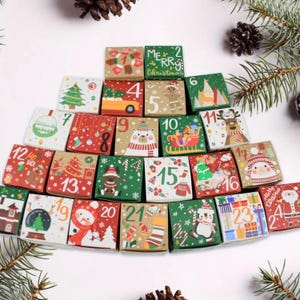 May include: A Christmas advent calendar with 24 numbered boxes, each with a different festive design. The boxes are arranged in a pyramid shape and feature illustrations of Santa Claus, snowmen, reindeer, and other holiday symbols.