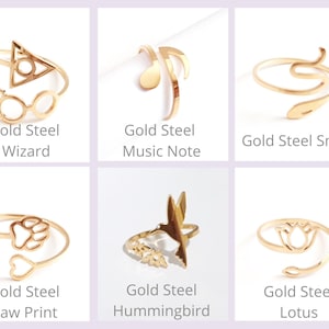 May include: Six gold-colored steel rings with various designs. The designs include a wizard symbol, musical note, snake, paw print, hummingbird, and lotus flower. Each ring has the words "Gold Steel" and a design name below it.