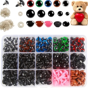 May include: A clear plastic storage box filled with various sizes and colors of plastic safety eyes for crafts. The box has 12 compartments, each filled with a different color or size of eyes. There are also loose safety eyes, washers, and a teddy bear in the image.