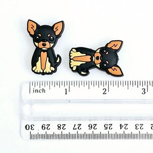 Puede incluir: Dos abalorios de perro chihuahua negro y marr&oacute;n, de aproximadamente 2,5 cm de tama&ntilde;o, sobre una regla.
