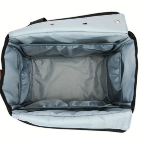 May include: An open black and light blue travel bag with multiple compartments and pockets. The bag is lined with a light blue fabric.