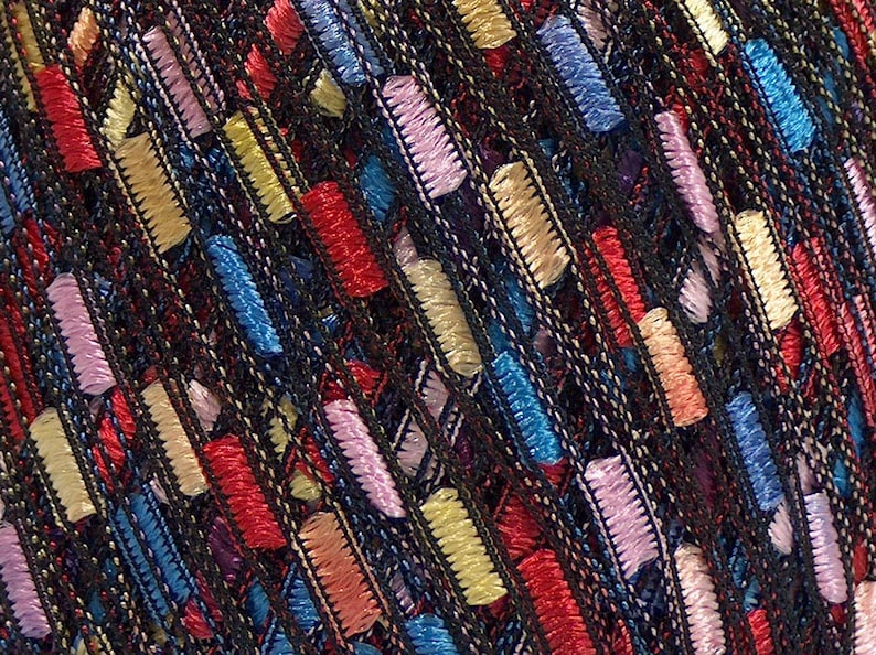 Puede incluir: Primer plano de un textil con un fondo oscuro y acentos bordados rectangulares coloridos. Los acentos son en tonos de rojo, amarillo, azul y rosa, creando un dise&ntilde;o texturizado y estampado. El bordado es detallado y est&aacute; tejido apretadamente.
